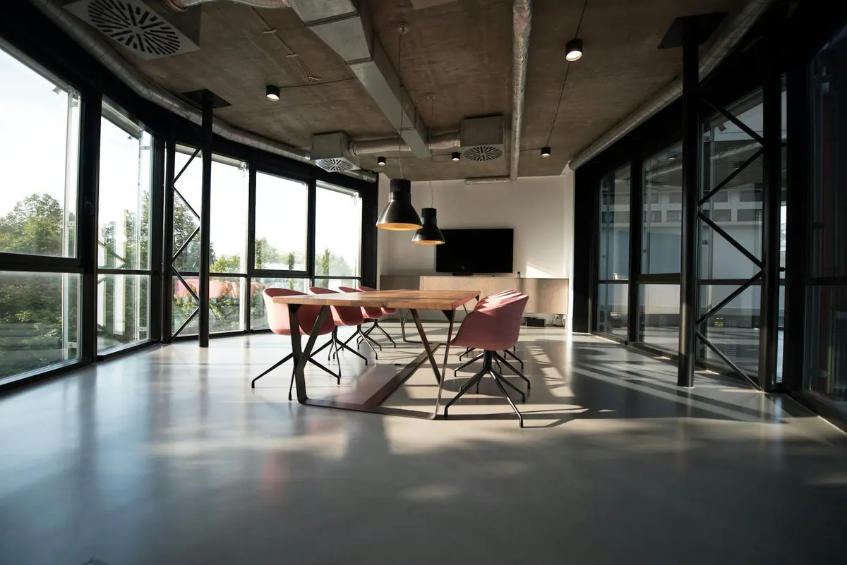 A long meeting table and chairs in a bright, glass-walled room