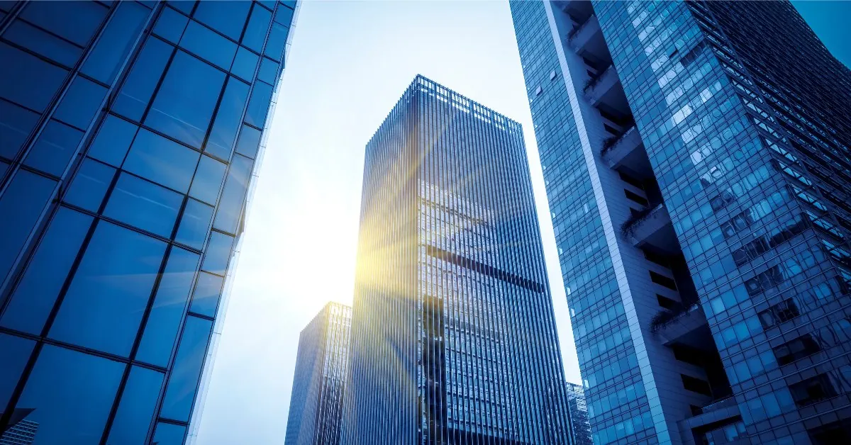 Glass office towers with the sun breaking between them — business, employment and company law