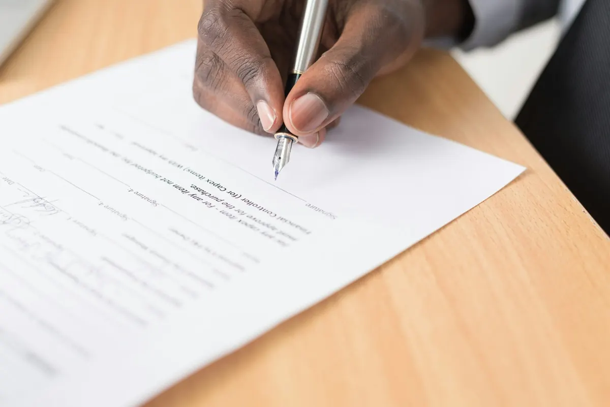 The signature A hand signing a document with a fountain pen