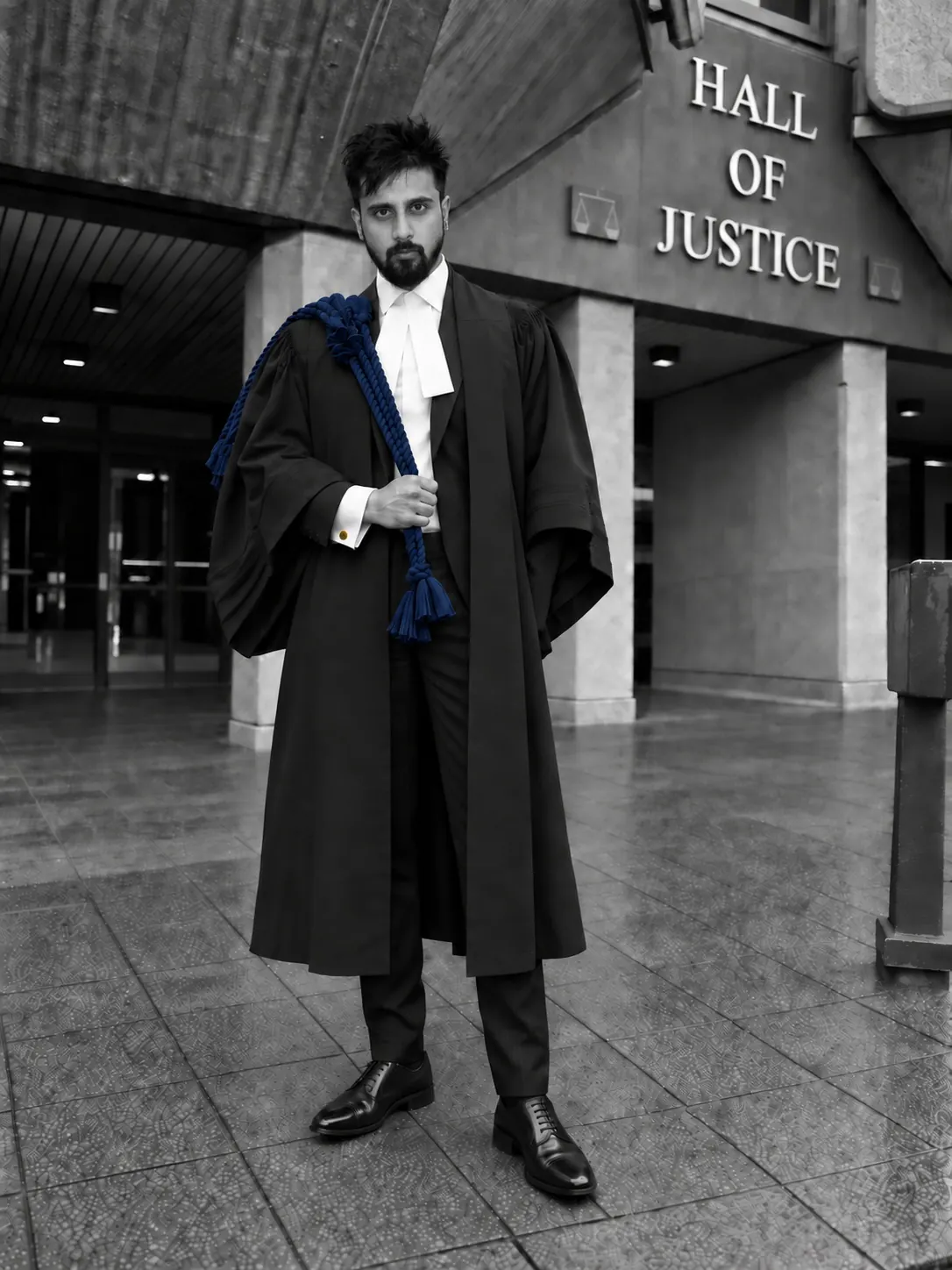 Suraj Sakal, Attorney-at-Law, in gown and bands outside the Hall of Justice, Port of Spain, the building's name carved on the wall behind